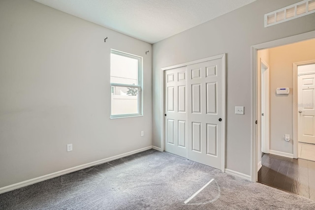 unfurnished bedroom featuring a closet, dark wood-type flooring, and a textured ceiling