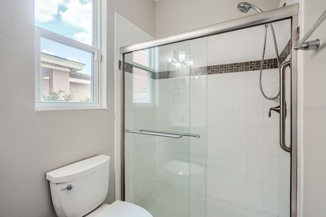 bathroom featuring toilet and a shower with shower door