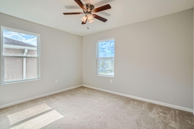 carpeted empty room featuring a wealth of natural light and ceiling fan