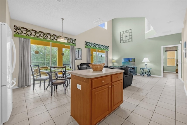 kitchen with hanging light fixtures, a kitchen island, white fridge, a textured ceiling, and light tile patterned floors