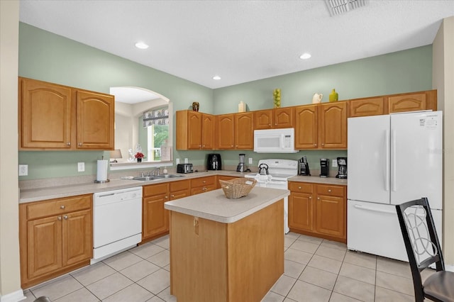 kitchen with a textured ceiling, white appliances, sink, a kitchen island, and light tile patterned flooring