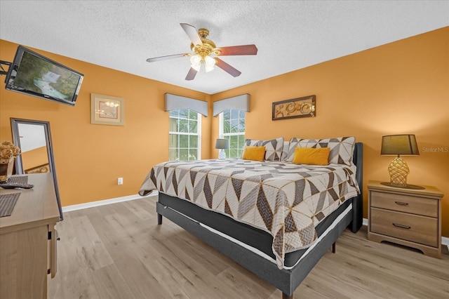 bedroom featuring ceiling fan, light wood-type flooring, and a textured ceiling