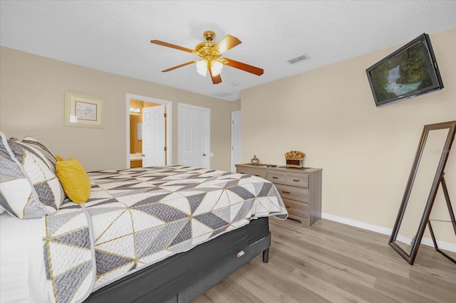 bedroom with a textured ceiling, ensuite bath, light hardwood / wood-style flooring, and ceiling fan