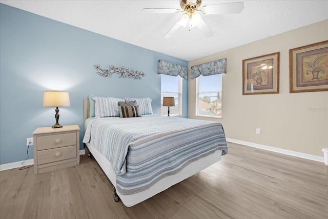 bedroom with ceiling fan, light wood-type flooring, and a textured ceiling