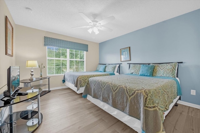 bedroom with ceiling fan, a textured ceiling, and hardwood / wood-style flooring