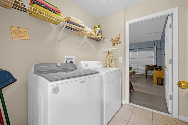 washroom featuring washer and clothes dryer, light tile patterned floors, and a textured ceiling