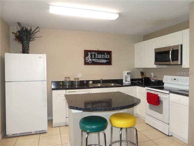 kitchen featuring white appliances, sink, light tile patterned floors, a center island, and white cabinetry