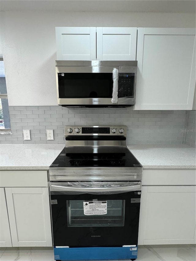 kitchen featuring white cabinets, light stone counters, and appliances with stainless steel finishes