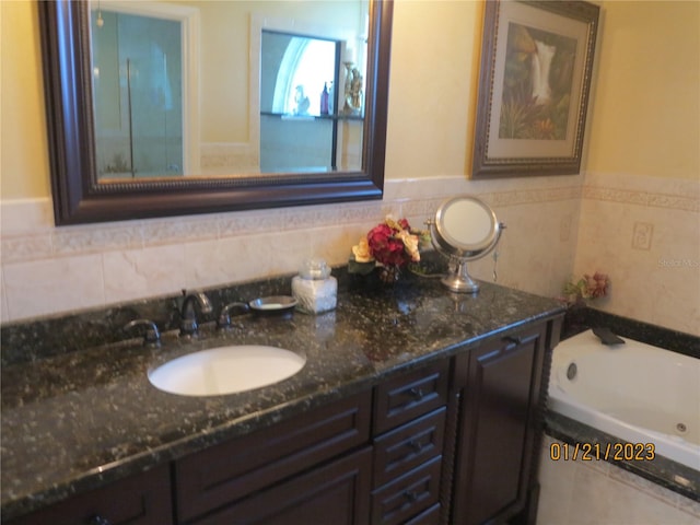 bathroom featuring vanity, a bathtub, and tile walls