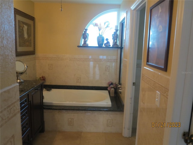 bathroom with vanity, tile patterned floors, tile walls, and tiled tub