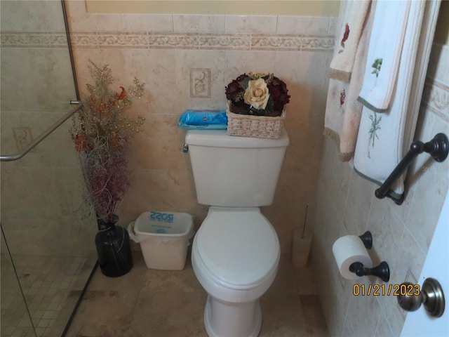 bathroom featuring tile patterned floors, toilet, and tile walls