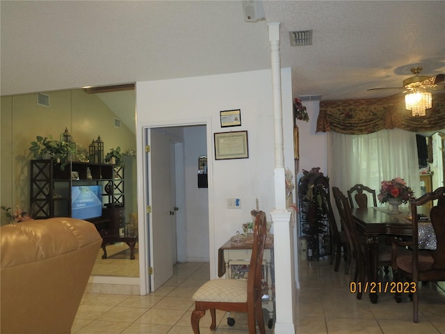 tiled dining area with ceiling fan, lofted ceiling, and a textured ceiling