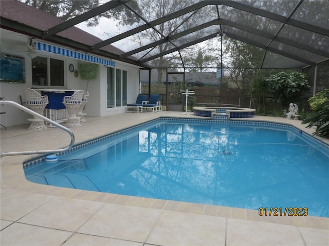 view of swimming pool featuring glass enclosure, an in ground hot tub, and a patio area