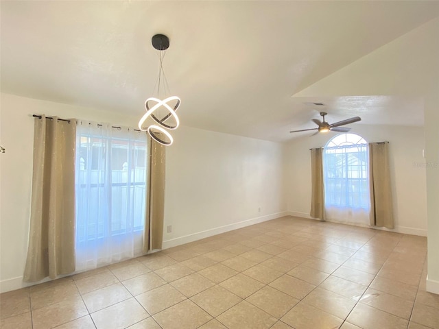 tiled empty room with ceiling fan with notable chandelier