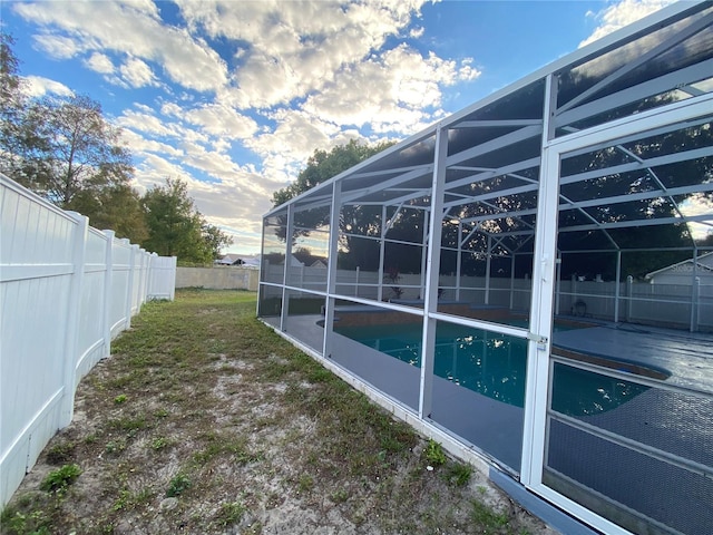 view of yard featuring glass enclosure, a fenced in pool, and a patio