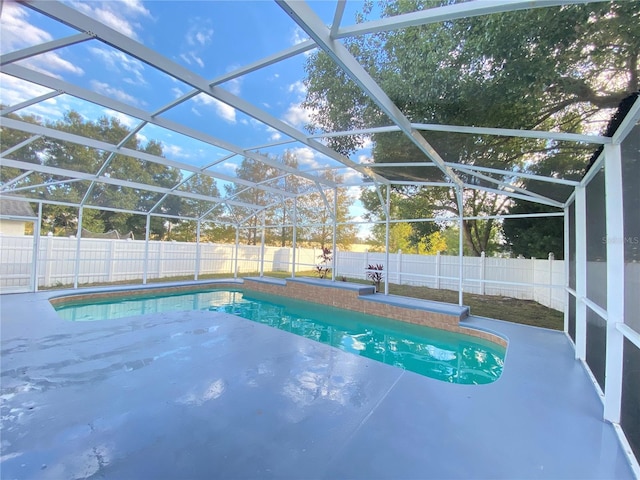 view of pool with glass enclosure and a patio