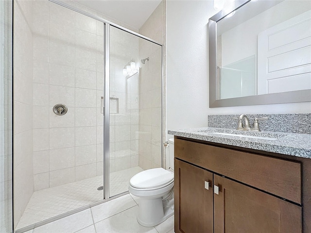 bathroom featuring tile patterned flooring, vanity, a shower with shower door, and toilet