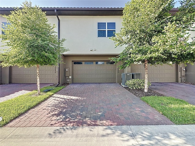 view of front of property featuring a garage and central AC