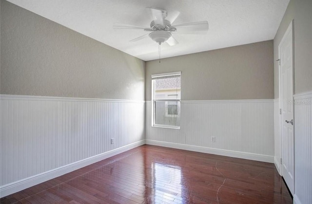 spare room with a textured ceiling, ceiling fan, and dark wood-type flooring