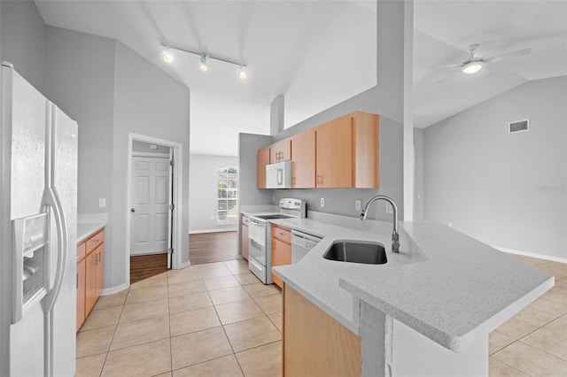 kitchen with light brown cabinets, white appliances, sink, light stone counters, and kitchen peninsula