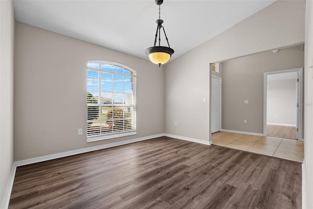 empty room featuring wood-type flooring and vaulted ceiling