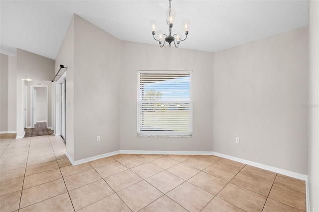 tiled empty room featuring a notable chandelier, a barn door, and lofted ceiling