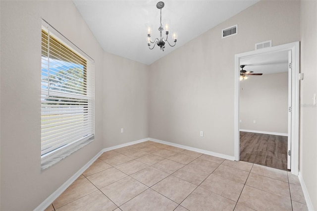 tiled spare room with ceiling fan with notable chandelier and vaulted ceiling