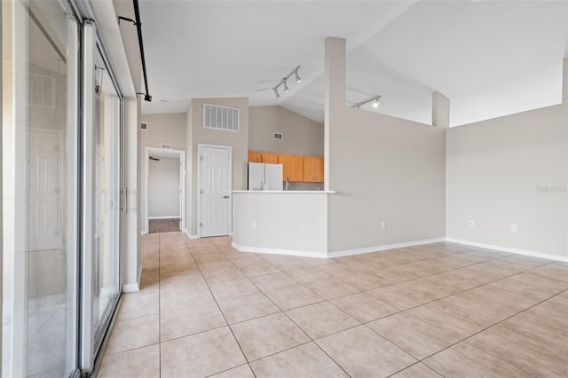 unfurnished living room with vaulted ceiling, light tile patterned flooring, and track lighting