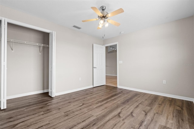 unfurnished bedroom with dark hardwood / wood-style flooring, a closet, and ceiling fan