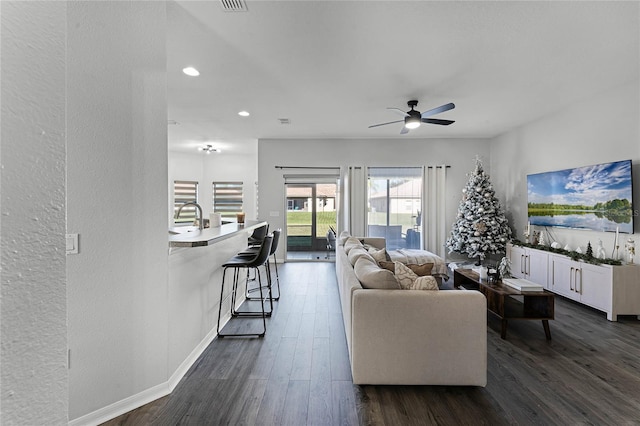 living room with dark hardwood / wood-style floors, ceiling fan, and sink