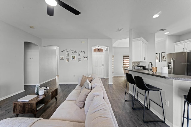 living room with ceiling fan and dark wood-type flooring