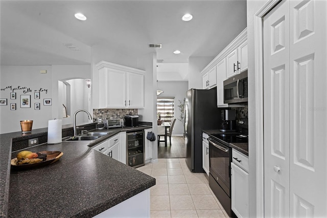 kitchen with kitchen peninsula, white cabinets, stainless steel appliances, and beverage cooler