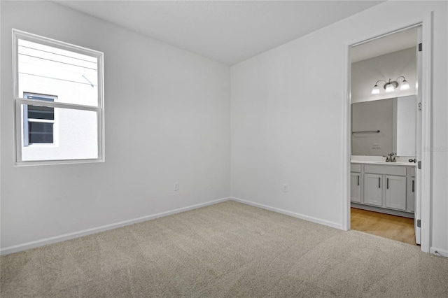 unfurnished bedroom with sink, ensuite bath, and light colored carpet