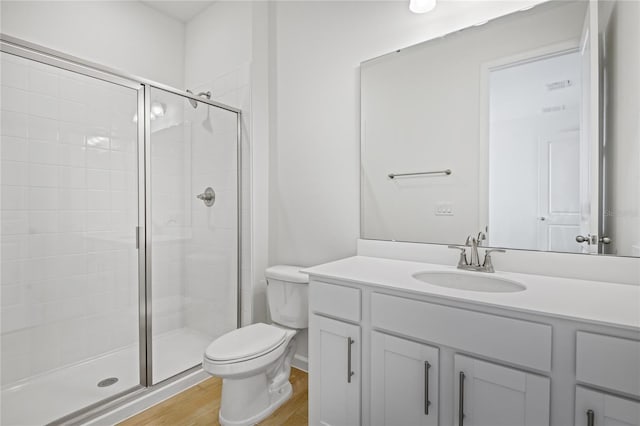 bathroom with vanity, wood-type flooring, a shower with shower door, and toilet