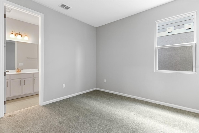 unfurnished bedroom featuring light colored carpet and connected bathroom