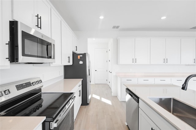 kitchen with appliances with stainless steel finishes, a sink, visible vents, and white cabinets