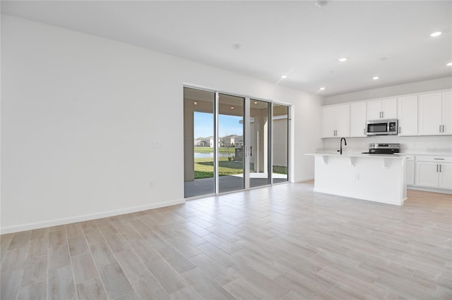 kitchen with recessed lighting, open floor plan, light countertops, appliances with stainless steel finishes, and light wood finished floors