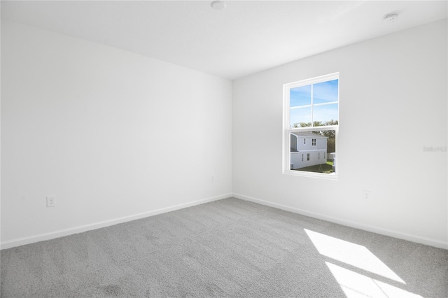 carpeted spare room featuring baseboards