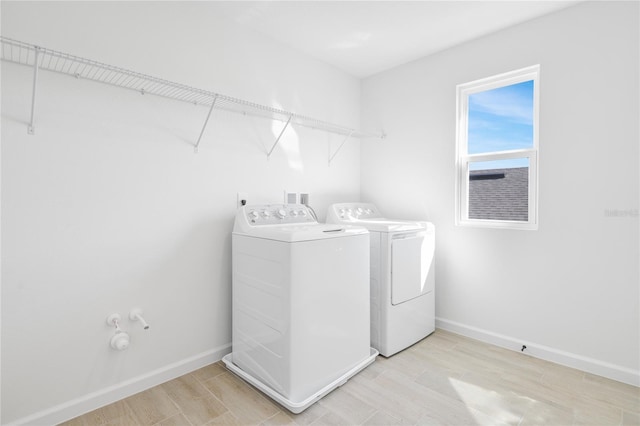 washroom featuring laundry area, light wood finished floors, independent washer and dryer, and baseboards