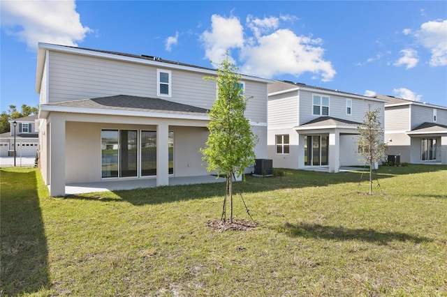 rear view of property featuring cooling unit, a lawn, and stucco siding