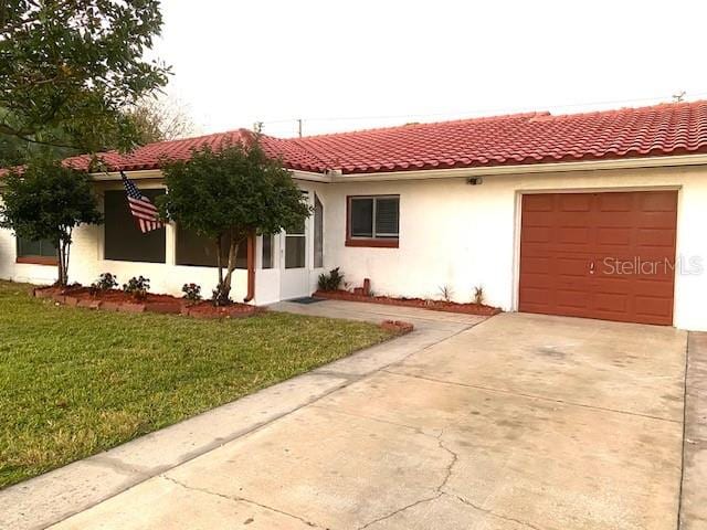 mediterranean / spanish-style home with a garage and a front lawn