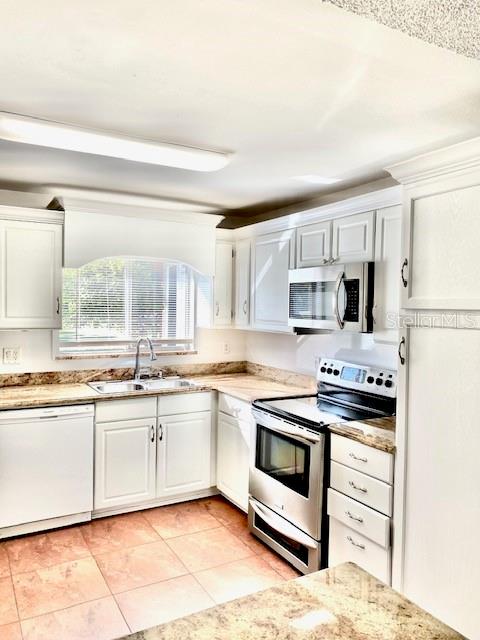 kitchen featuring white cabinets, light tile patterned floors, sink, and appliances with stainless steel finishes