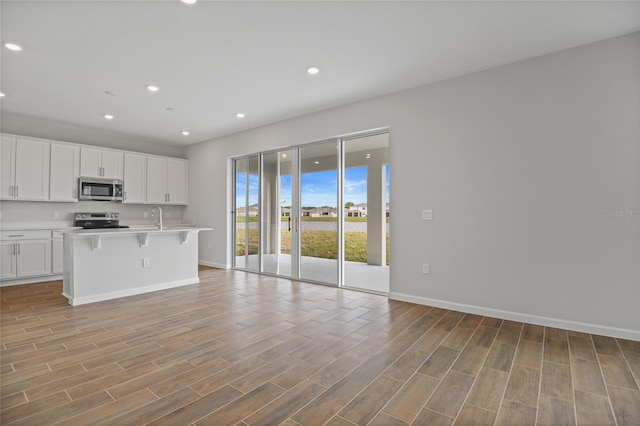 kitchen featuring sink, a breakfast bar, white cabinetry, a kitchen island with sink, and stainless steel appliances