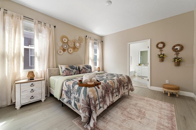 bedroom featuring ensuite bathroom and light hardwood / wood-style flooring