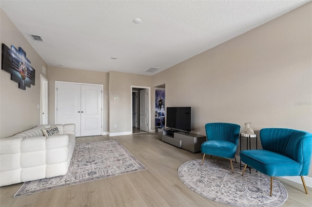 living room with a textured ceiling and light hardwood / wood-style flooring