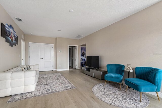 living room featuring light hardwood / wood-style floors and a textured ceiling