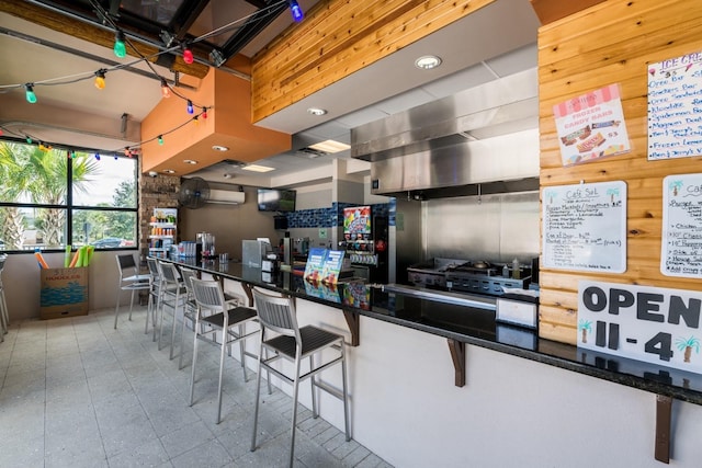 kitchen featuring a kitchen bar, a wall mounted AC, and wooden walls