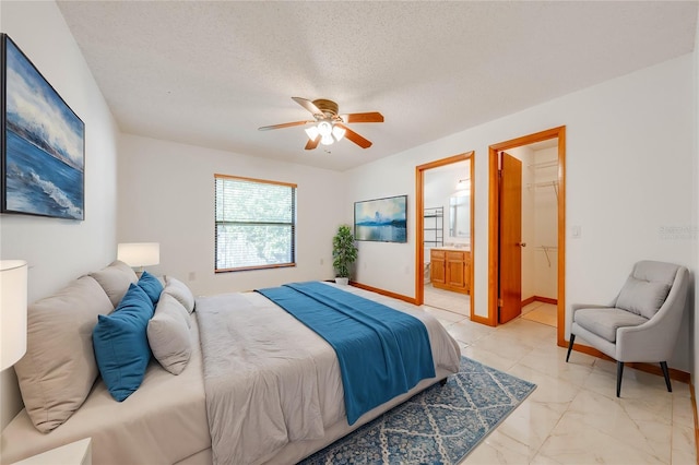 bedroom with ensuite bathroom, ceiling fan, a spacious closet, a textured ceiling, and a closet