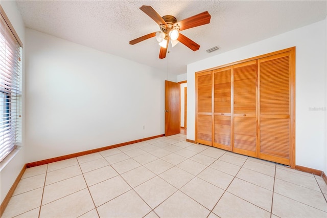 unfurnished bedroom featuring a textured ceiling, a closet, ceiling fan, and light tile patterned flooring