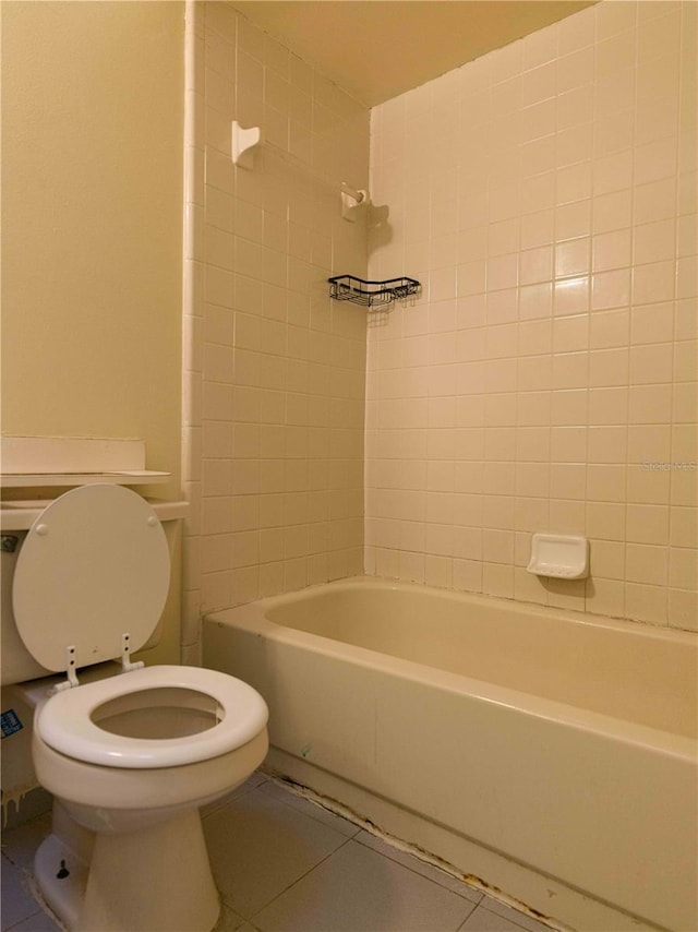 bathroom with toilet, tile patterned flooring, and tiled shower / bath